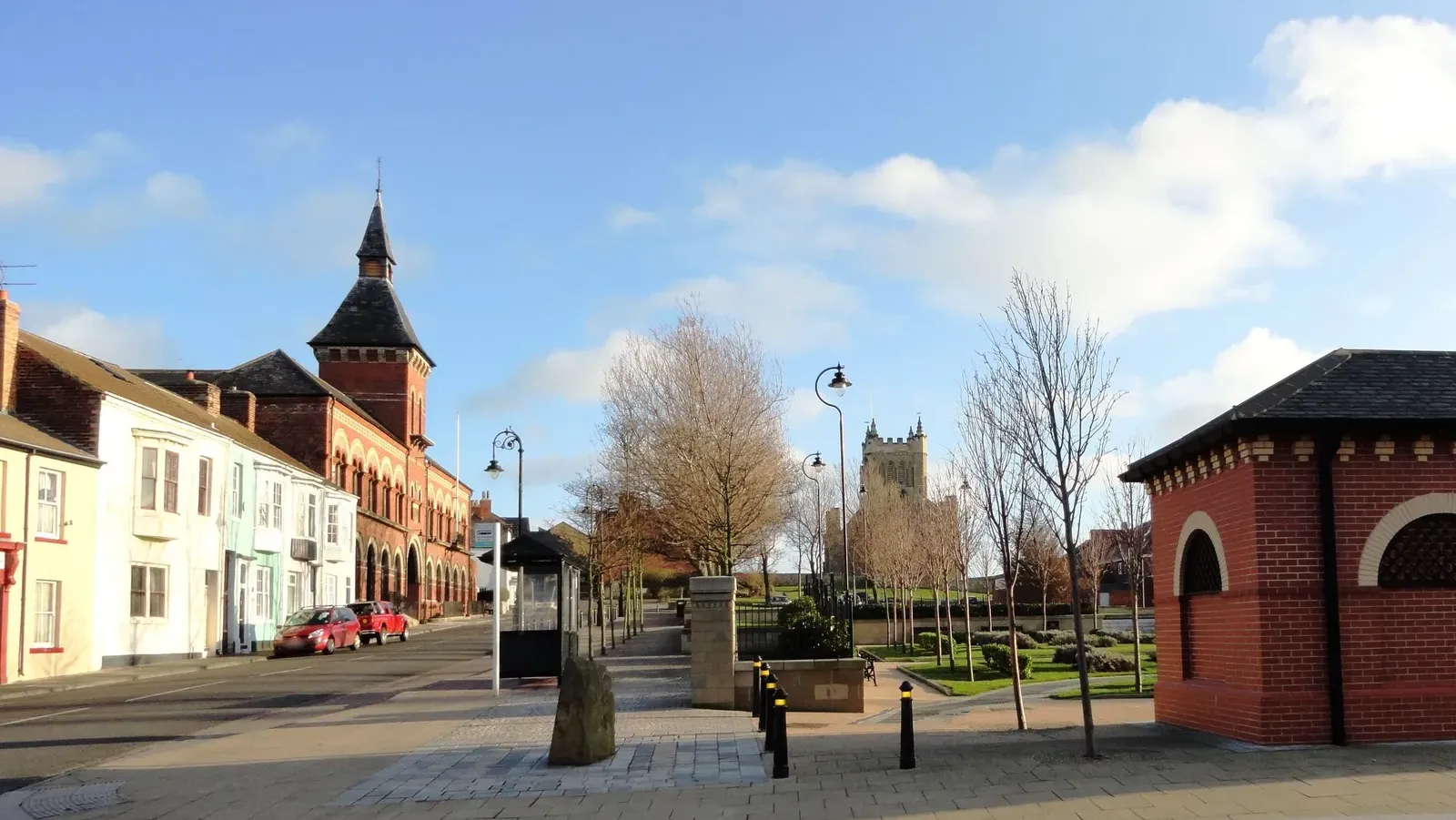 Hartlepool's Headland on a sunny winter day, looking from Northgate across a small park to the tower of St Hilda's Church, with red-brick buildings and painted terraced houses along the street