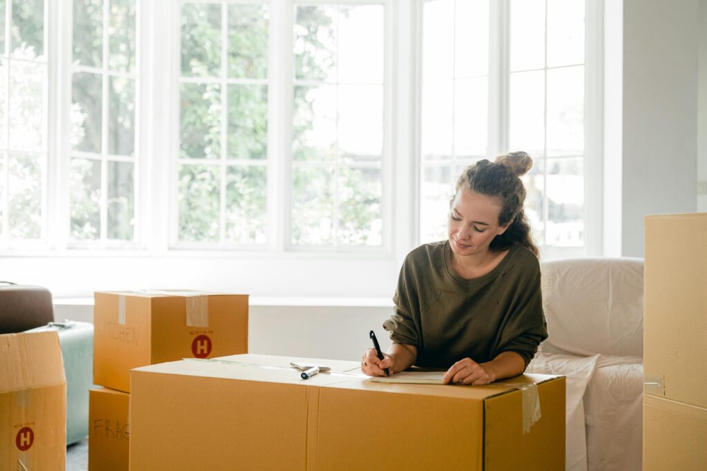 Woman labelling moving boxes while preparing for a home move
