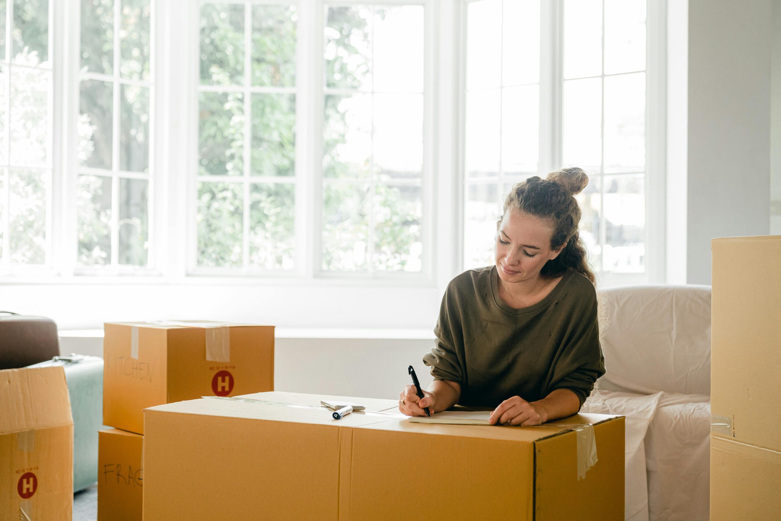 Woman labelling moving boxes while preparing for a home move